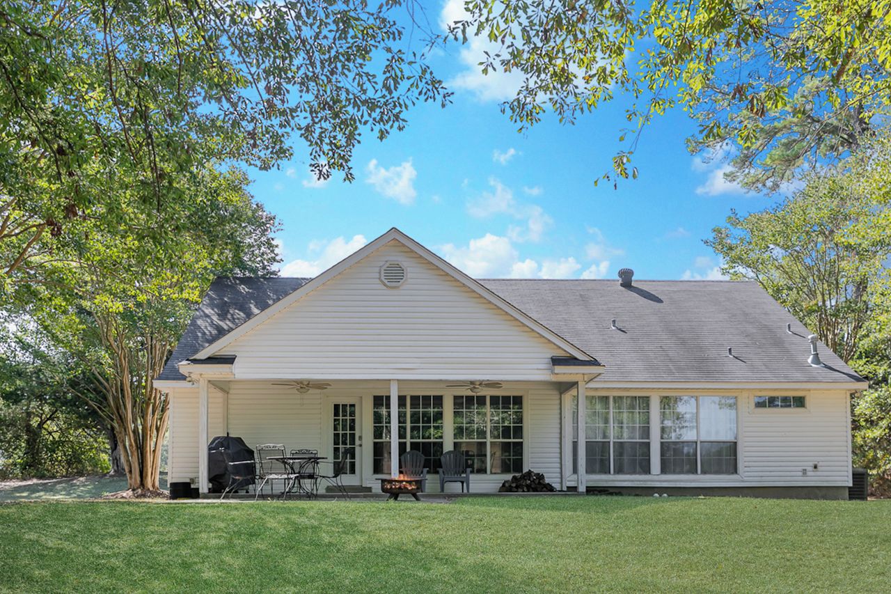 A single-story house with a covered patio, a grill, and a fire pit.