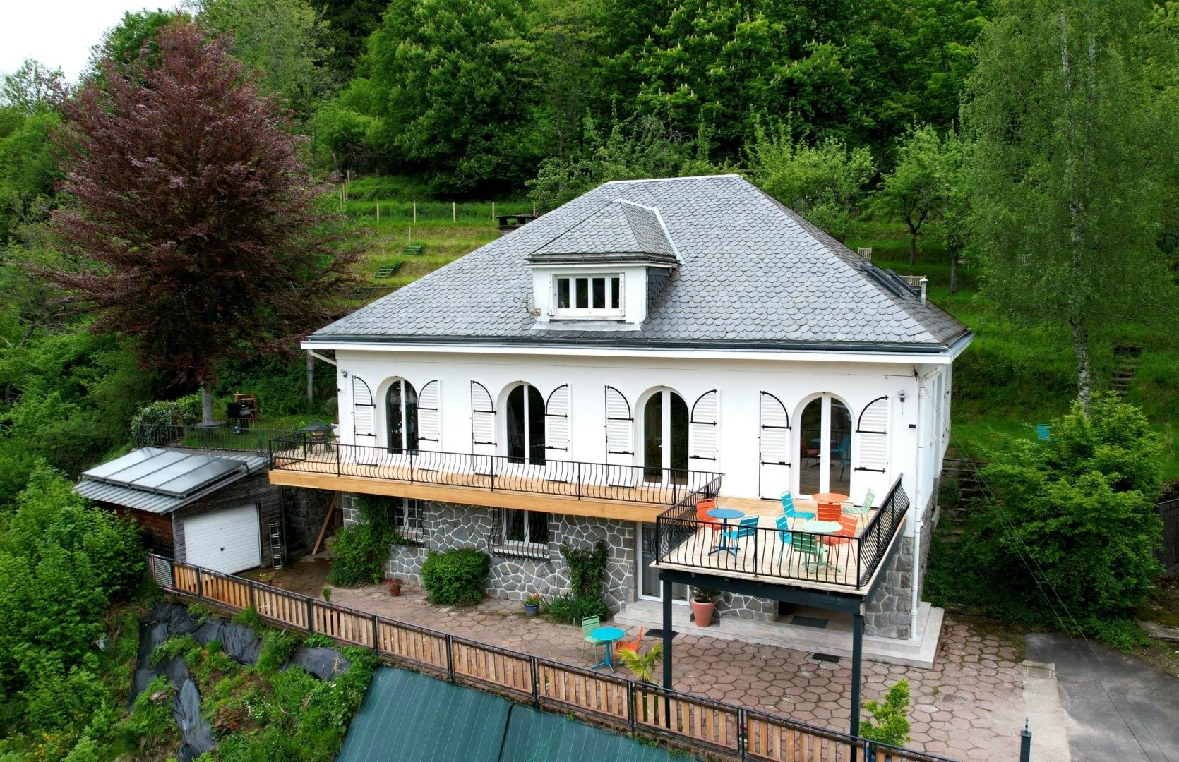 Ein zweistöckiges Haus mit Balkon, Stein Fundament und einer kleinen angebauten Garage.