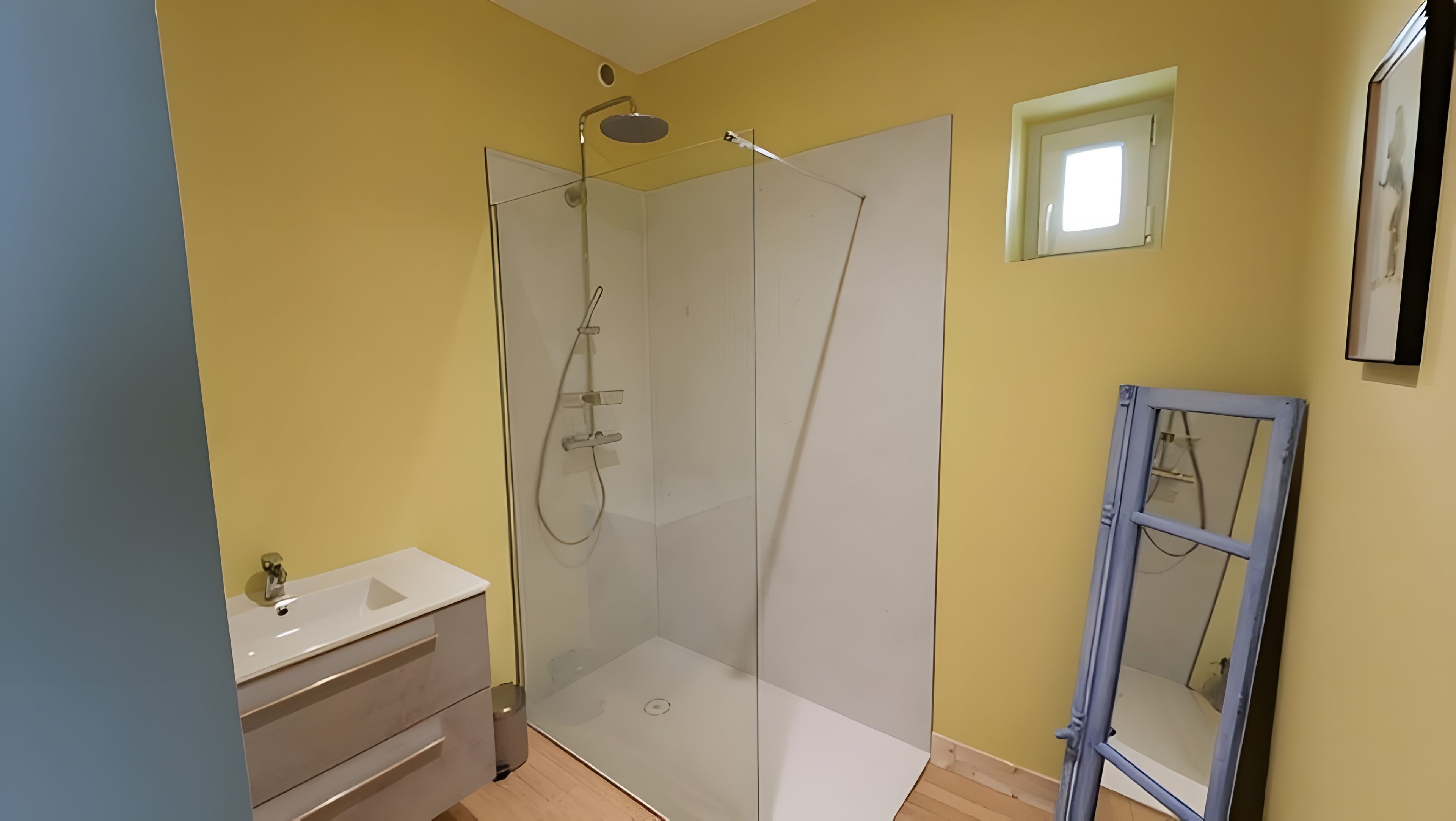 Une salle de bain avec une douche à parois de verre, un lavabo blanc et un miroir.