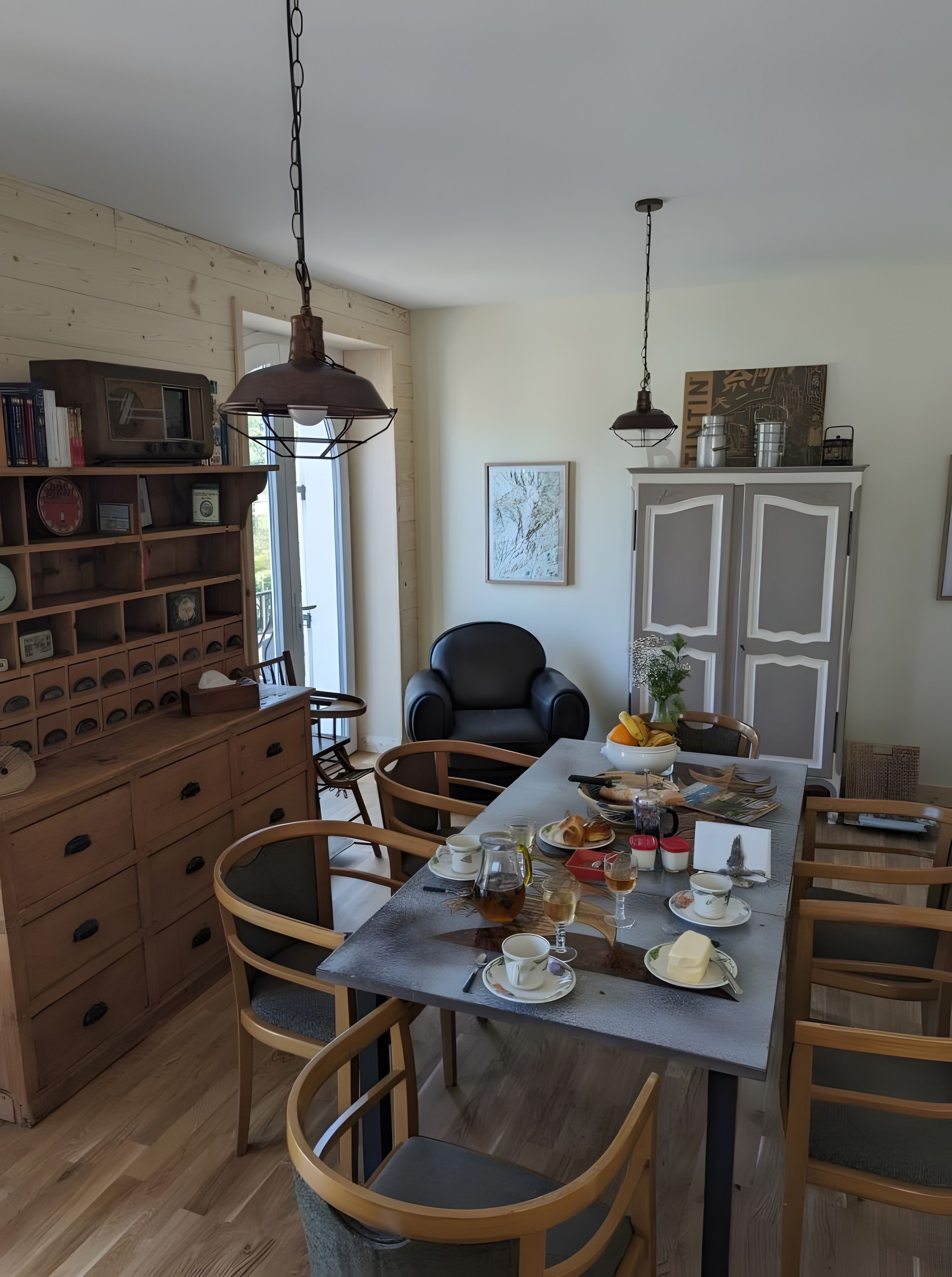 Een eethoek met een houten tafel, stoelen en een kast met diverse spullen.