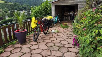 Een geplaveid buitengebied met fietsen, een potplant en een houten constructie.