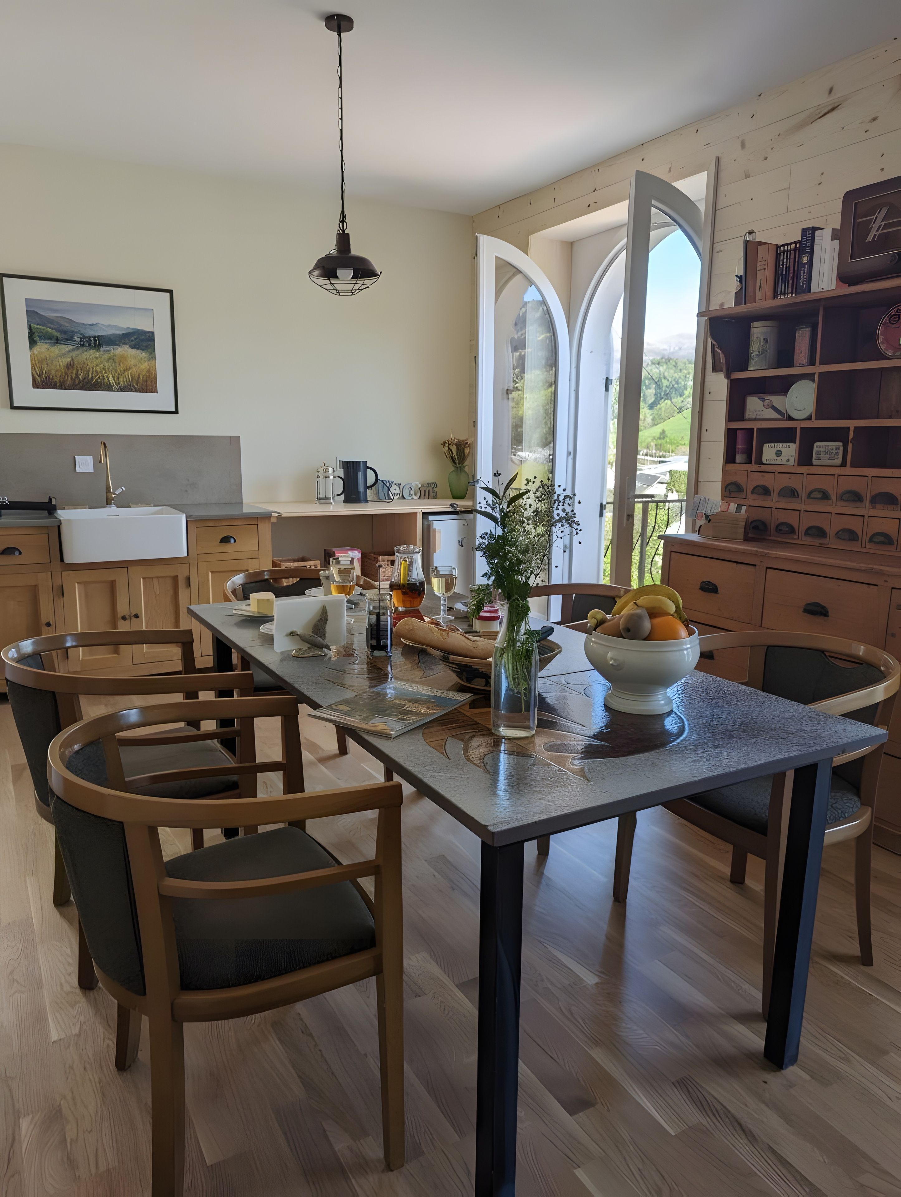 Een eetgedeelte met een houten tafel, stoelen en uitzicht door een open deur.