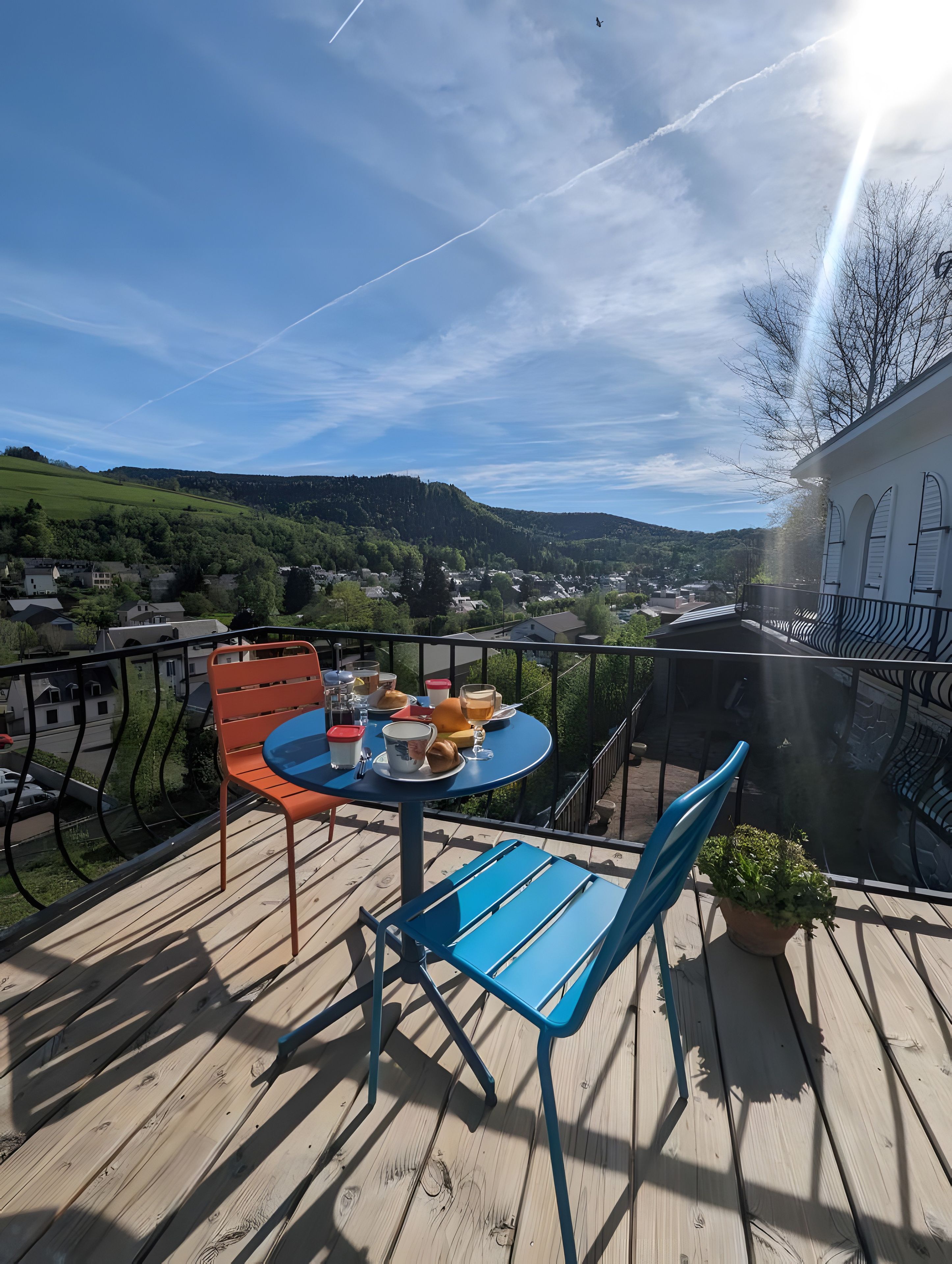 Een balkon met een tafel en stoelen, met uitzicht op een stad en heuvels.