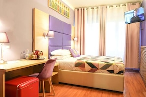 A hotel room with a bed, a desk, a chair, a television, and a window with curtains. - Bobotel  (Florence)