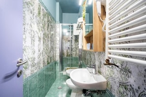 A bathroom with a glass shower enclosure, a sink, and a mirror with a wooden frame. - Bobotel  (Florence)