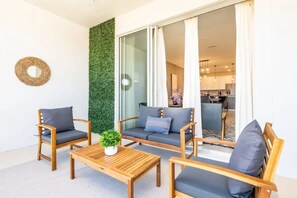 Ein modernes Wohnzimmer mit einem Holztisch, zwei Sofas mit grauen Kissen und einer vertikalen Grünwand.