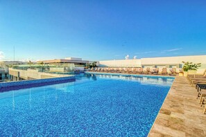 A rooftop swimming pool with lounge chairs and a clear sky. - 1BR Condo Rooftop Pool & Gym Playa (Playa del Carmen)