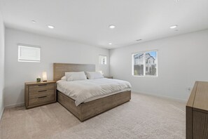 A bedroom with a bed, a nightstand, a dresser, and a window with blinds. - Spacious West Sac Retreat - Park, Patio & BBQ (West Sacramento)