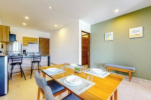 A modern kitchen with a dining area, wooden furniture, and a bench. - 2BR Condo Near Akumal Beach, Rooftop Pool (Akumal)