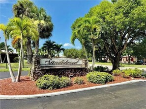 A sign with the name 'Sandalwood' surrounded by landscaped areas with palm trees and shrubs. - Coastal Glam / Near Beach & Downtown / Heated Pool (Fort Myers)