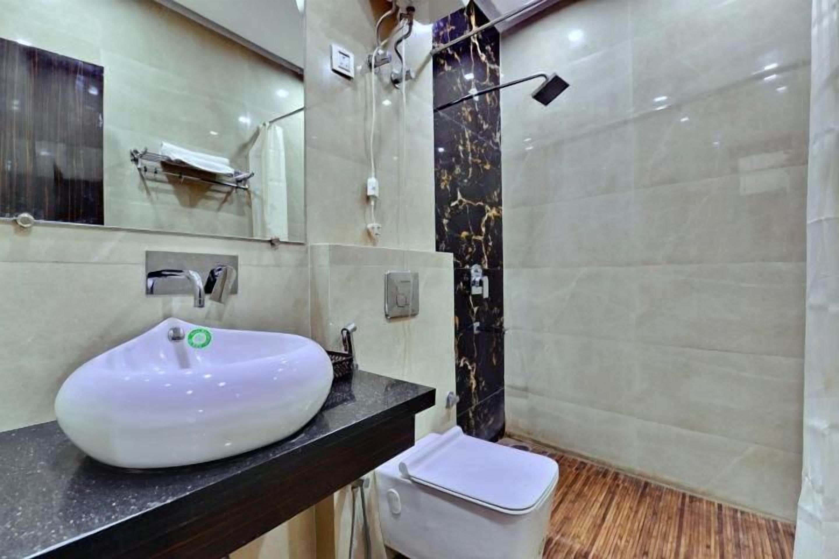 Une salle de bain avec un lavabo blanc, un miroir et un espace douche.