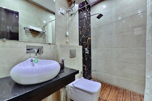 Baño con lavamanos blanco, espejo y zona de ducha.