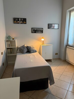 A bedroom with a bed, bedside tables, a radiator, and wall art. - Apartment 'Molo 61' with Private Garden and Wi-Fi (Roma)