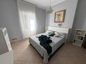 Un dormitorio ordenado con cama, mesita de noche y estantería.