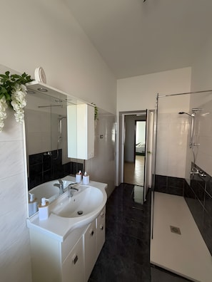 A modern bathroom with a double sink vanity, a glass shower enclosure, and a visible door leading to another room. - Apartment 'Molo 61' with Private Garden and Wi-Fi (Roma)