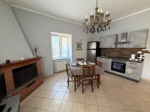 A modern kitchen with a dining area, a fireplace, and a chandelier. - Apartment 'Molo 61' with Private Garden and Wi-Fi (Roma)