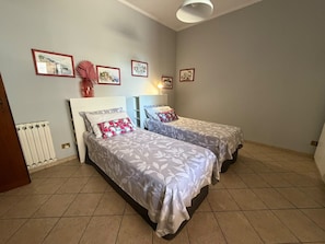 A bedroom with two beds, a radiator, and framed pictures on the wall. - Apartment 'Molo 61' with Private Garden and Wi-Fi (Roma)