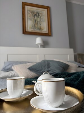 Un lit avec une tête de lit blanche, une table de chevet avec une lampe blanche et un tableau encadré au mur.