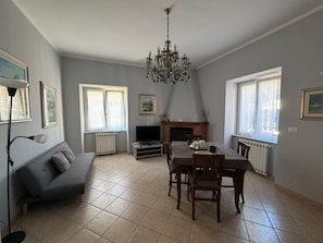 Un salon comprenant un canapé, une table à manger, des chaises, une cheminée et un lustre.