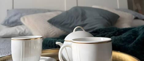 A bed with a white headboard, a bedside table with a lamp, and a green blanket.