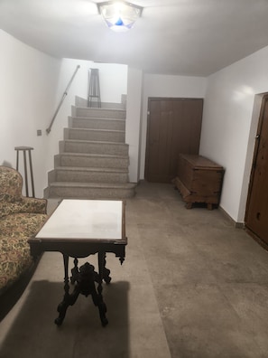 A room with a staircase, a wooden cabinet, a small table, and a floral sofa. - Holiday Home 'Casa Josefina' with Mountain View, Private Terrace and Wi-Fi (Dólar)