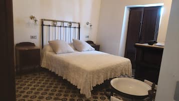 A bedroom with a bed, a nightstand, a dresser, a mirror, and a bathroom with a sink and toilet.