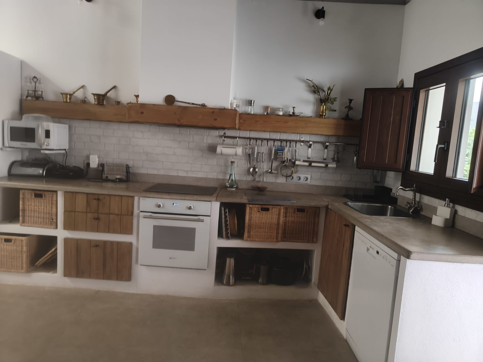 A kitchen with white cabinets, a microwave, a stove, and a sink.