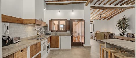 A modern kitchen with wooden beams, a central island, and a dining area with bar stools.