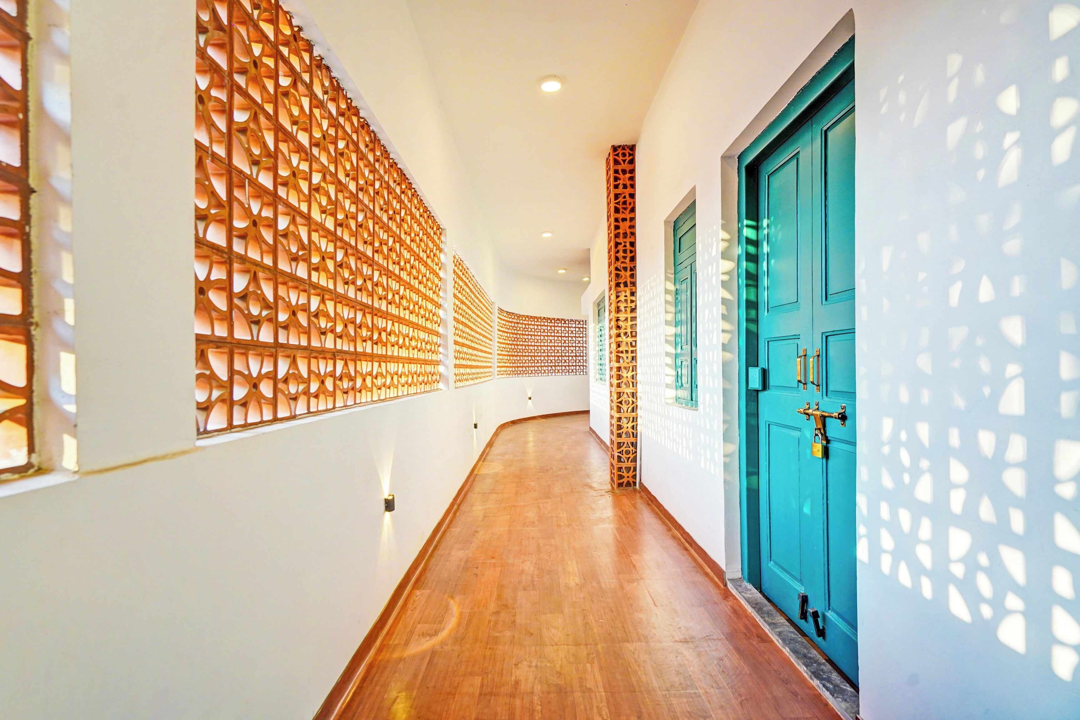 Un couloir doté d’un plancher en bois, d’une porte de couleur turquoise et de panneaux décoratifs en bois sur les murs.