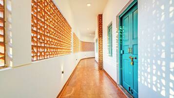 Un couloir doté d’un plancher en bois, d’une porte de couleur turquoise et de panneaux décoratifs en bois sur les murs.