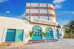 Un hotel con un letrero destacado que dice 'THE VANTAGE INN' y un diseño arquitectónico moderno con una fachada curva y puertas azules.