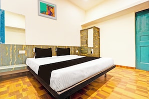 Una habitación de hotel con cama, armario, espejo y puerta.