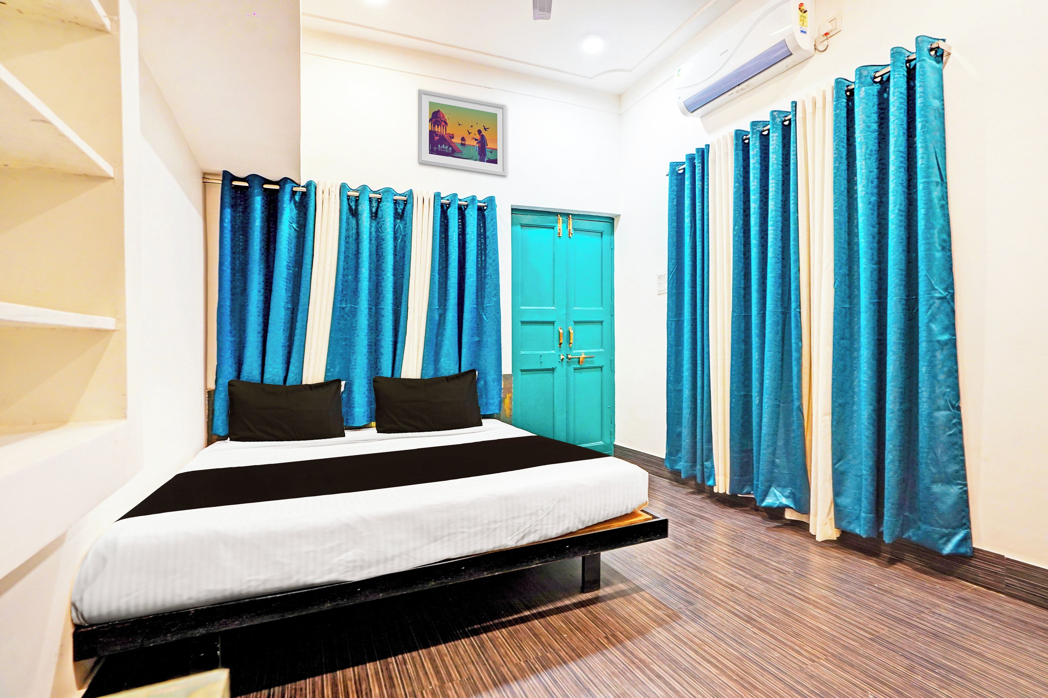 Una habitación de hotel con una cama, cortinas, una puerta y un cuadro en la pared.