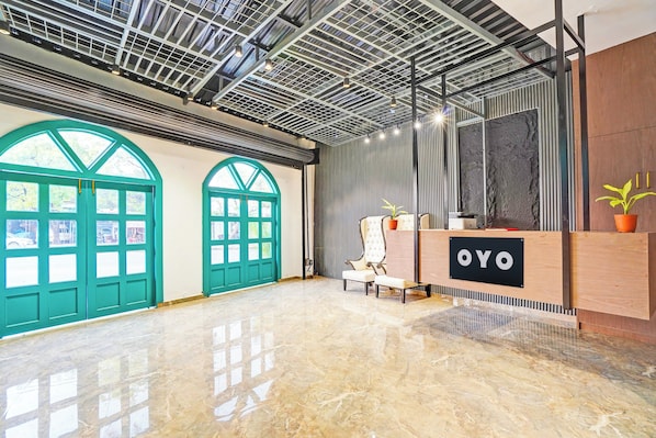 A spacious lobby with a high ceiling, large windows, and a reception desk labeled 'OYO'.