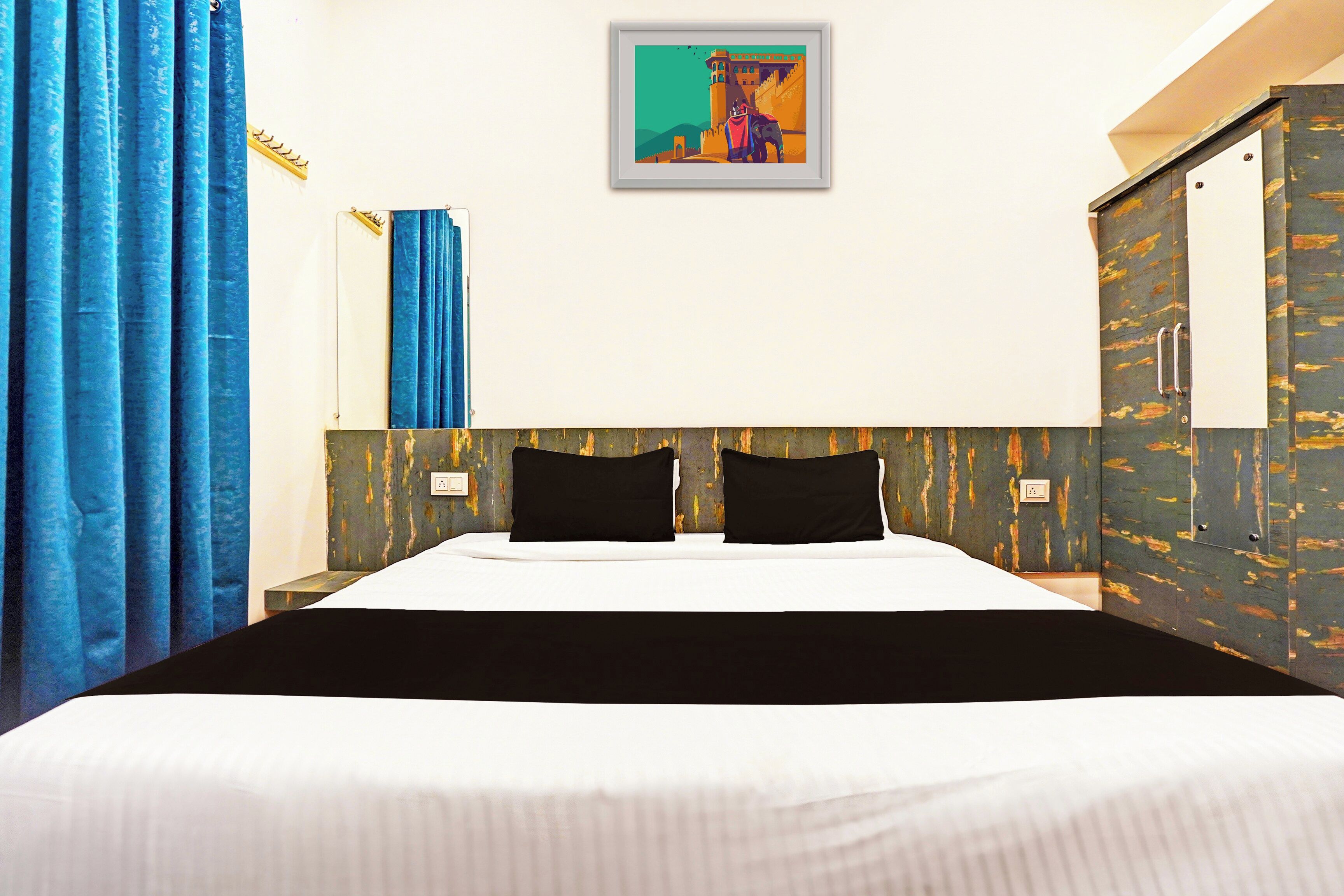 Une chambre d’hôtel avec un grand lit, un tableau au mur et une armoire.
