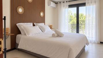 Une chambre à coucher comprenant un lit, un ventilateur de plafond, une fenêtre avec des rideaux et un climatiseur fixé au mur.