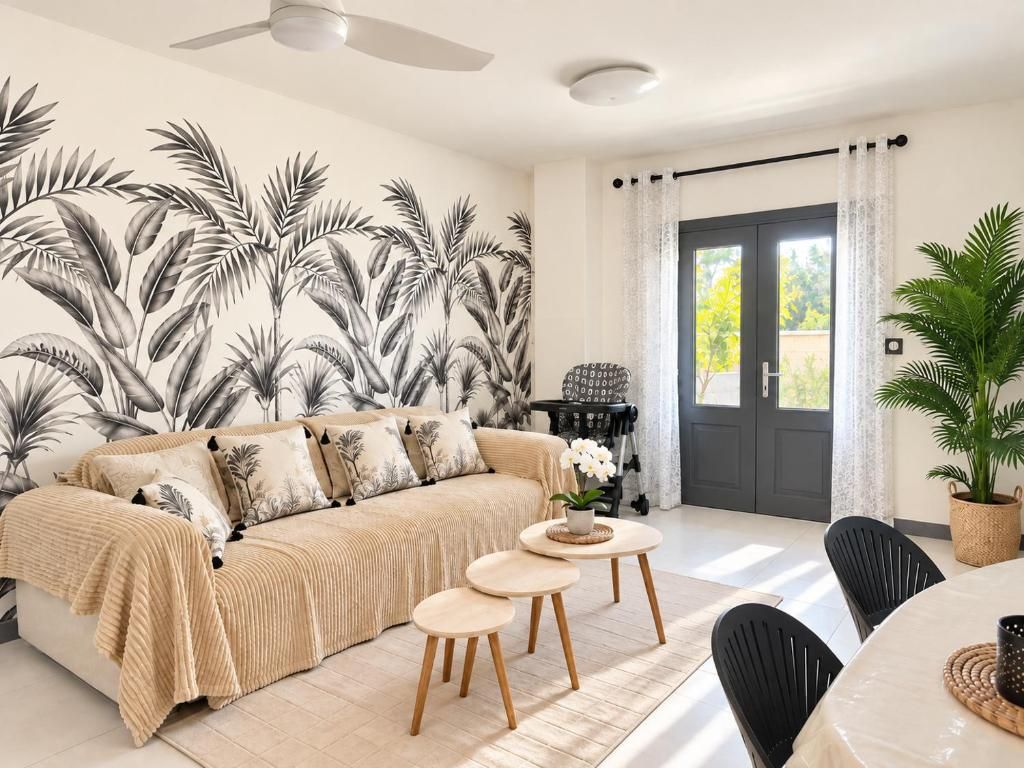 Un salon avec un canapé, deux petites tables, une plante en pot et une porte avec des rideaux.
