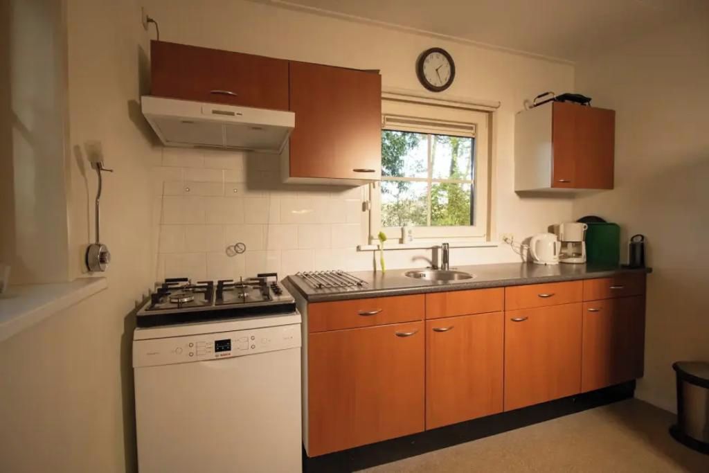 A kitchen with a stove, sink, cabinets, and a window.