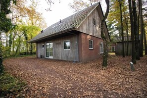 A rustic wooden house with a sloped roof, surrounded by trees and a leaf-covered ground. - Zwaontje 1–90 (Winterswijk)