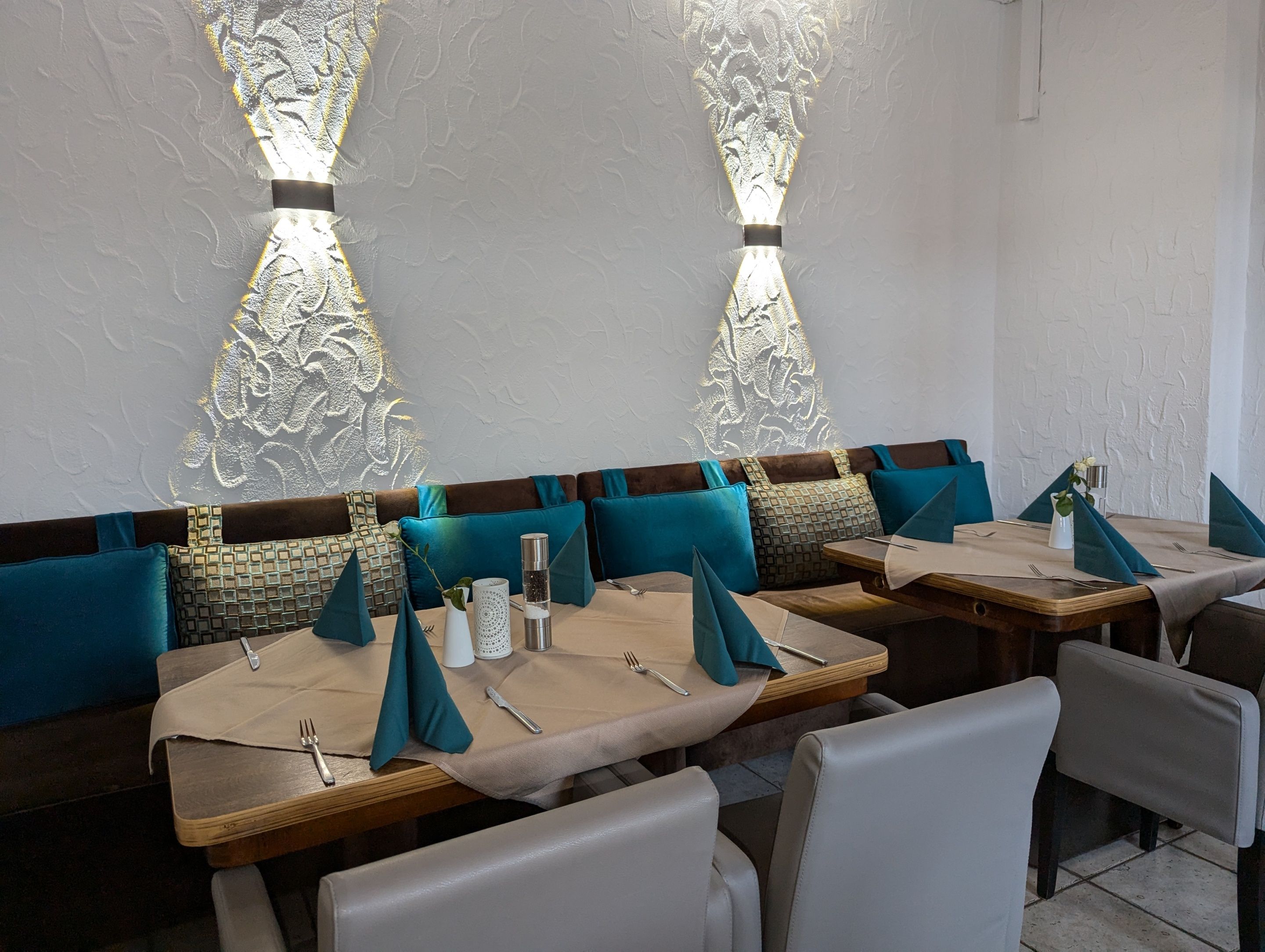 Ein Restaurantinneres mit Sitzecken, Tischen und einer Wand mit Muster.