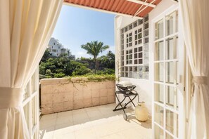 Ein Balkon mit Blick auf Grünflächen und Gebäude, inklusive Grill und Gasflasche.