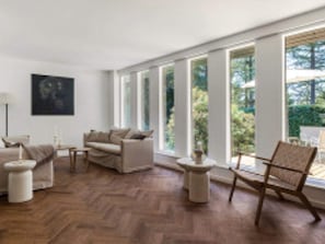 A modern living room with a sofa, armchairs, and a coffee table. There are large windows providing a view of the outdoors. - 12 Person Holiday Home in Vejby (Vejby)