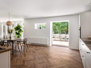 A modern kitchen with a herringbone wood floor, white cabinetry, and a view of the outdoors. - 12 Person Holiday Home in Vejby (Vejby)