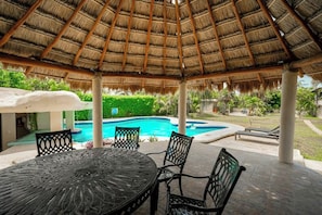 An outdoor patio with a thatched roof, a pool, and seating arrangements. - 4 Bedroom Villa, 3 Pools in Hotel Zone (Cancun)