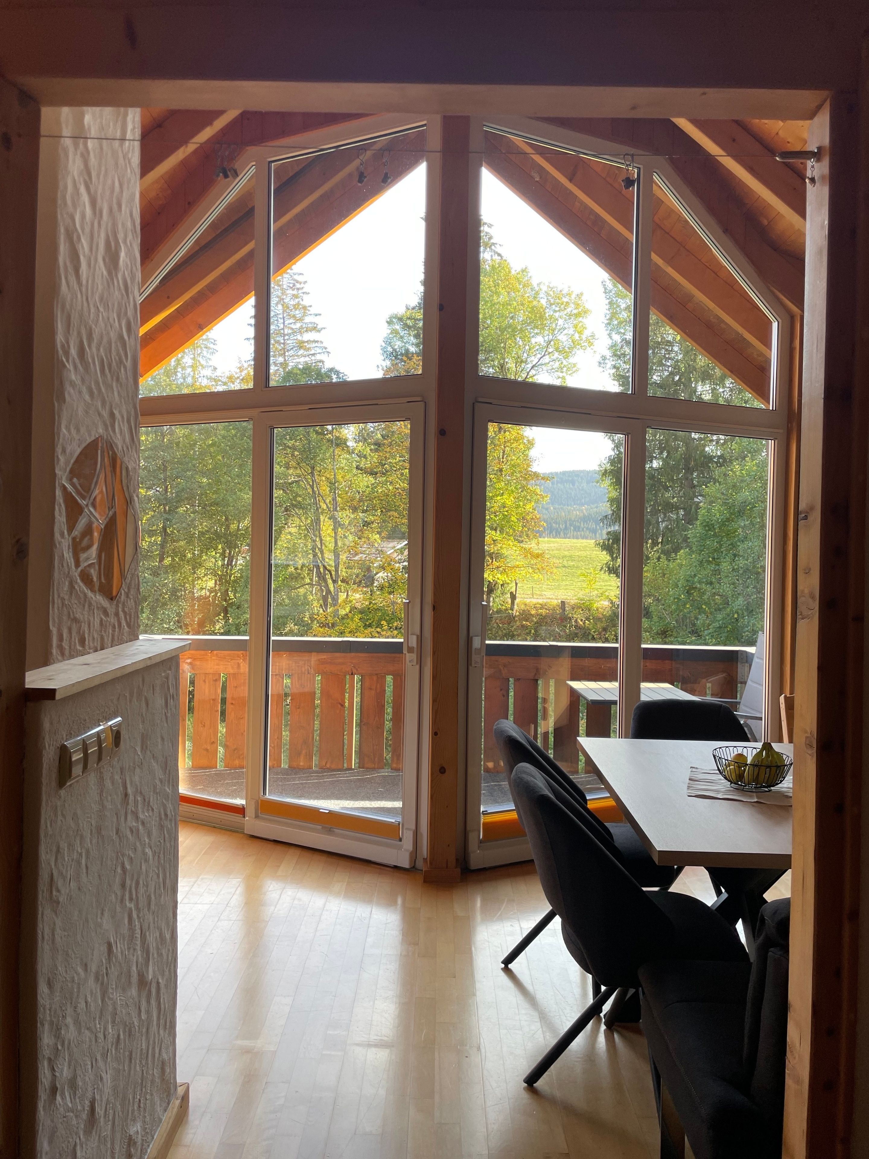 Ein Zimmer mit großem Fenster, Holzboden und einem Tisch mit Stühlen.