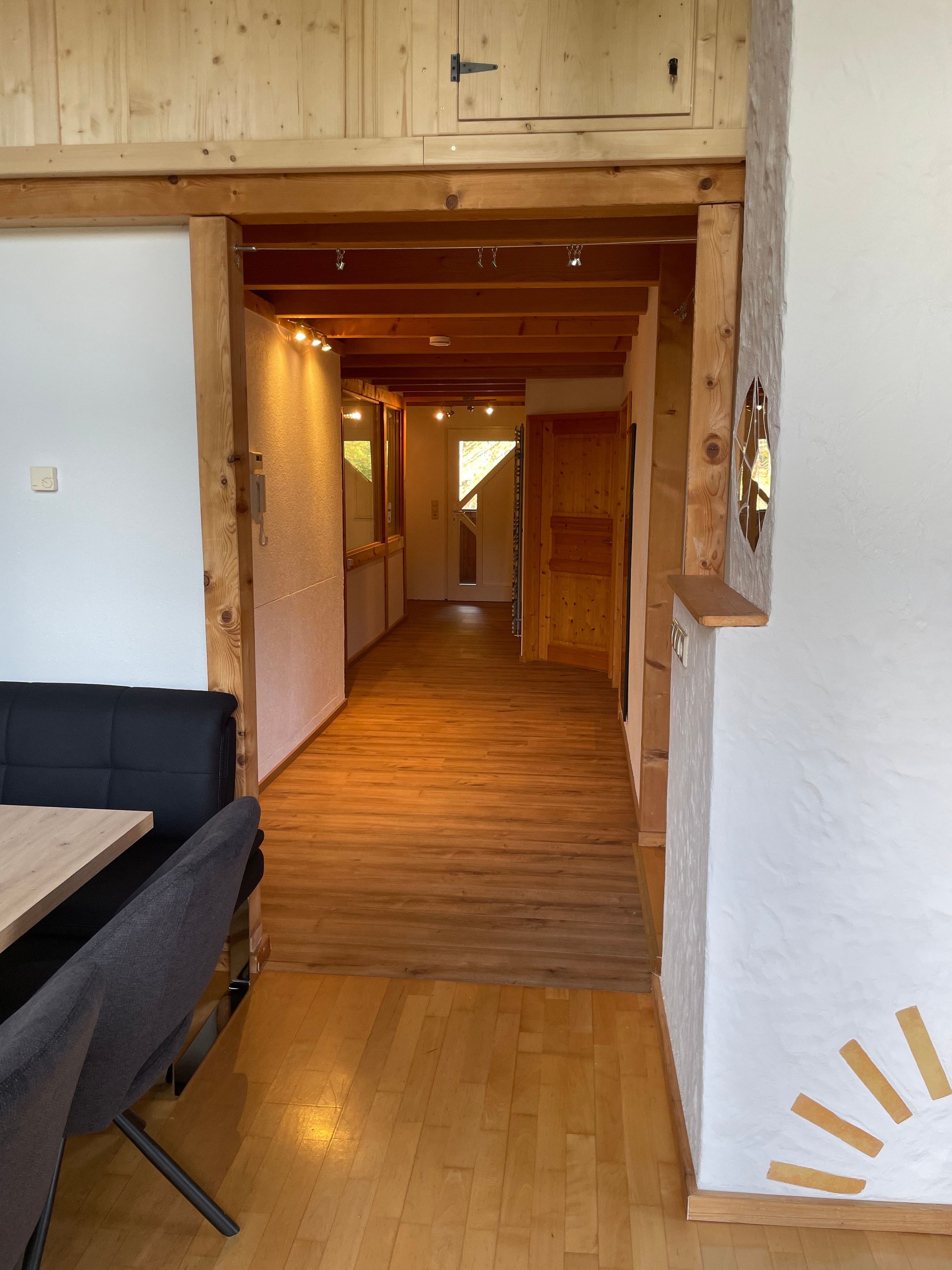 A wooden interior with a dining area, a staircase, and a hallway leading to another room.