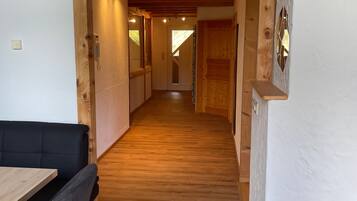 A wooden interior with a dining area, a staircase, and a hallway leading to another room.
