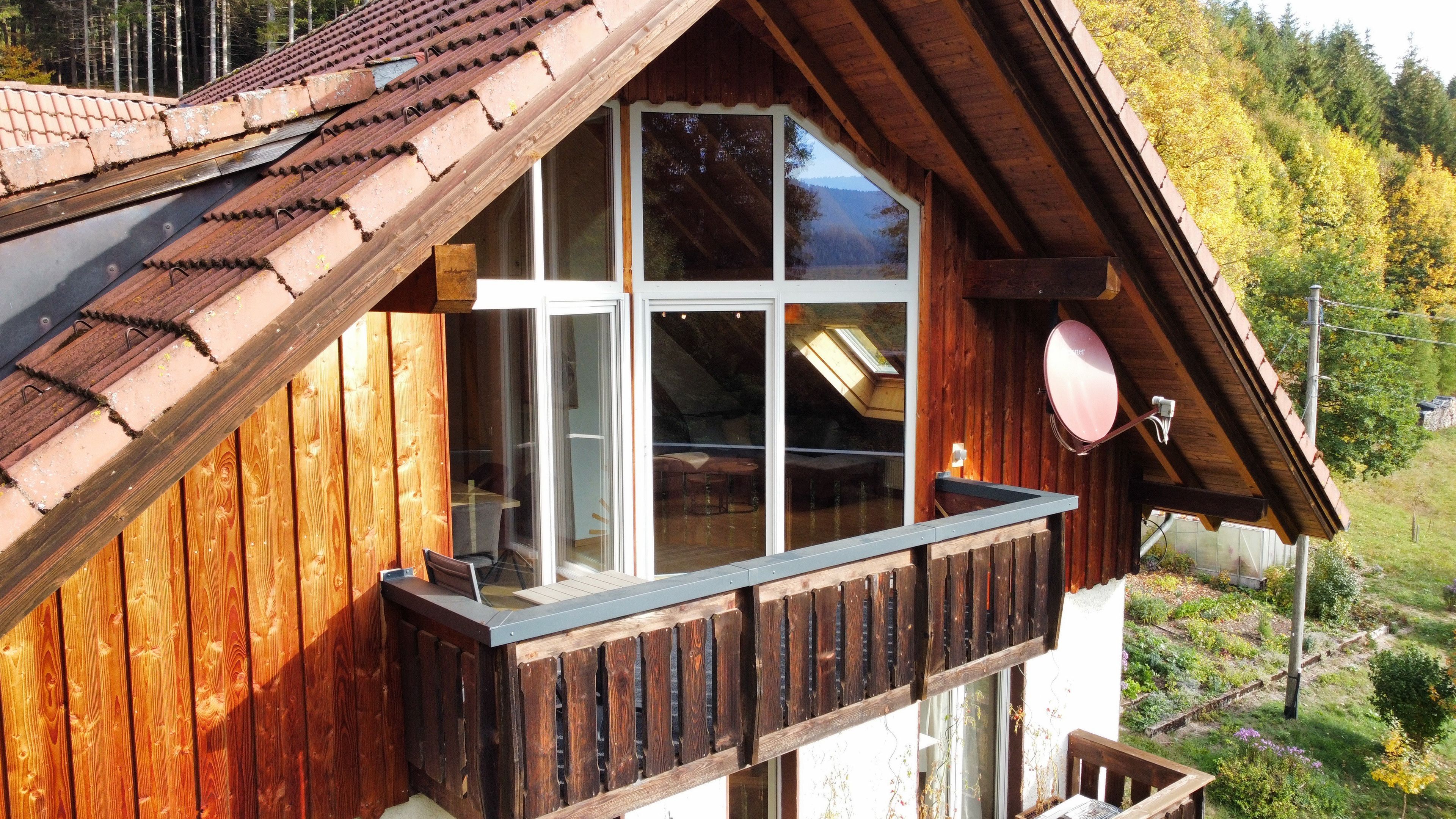 Eine Holzhütte mit Balkon, großen Fenstern und einer Satellitenschüssel.