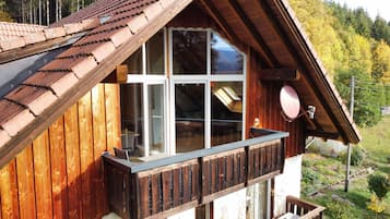 Eine Holzhütte mit Balkon, großen Fenstern und einer Satellitenschüssel.