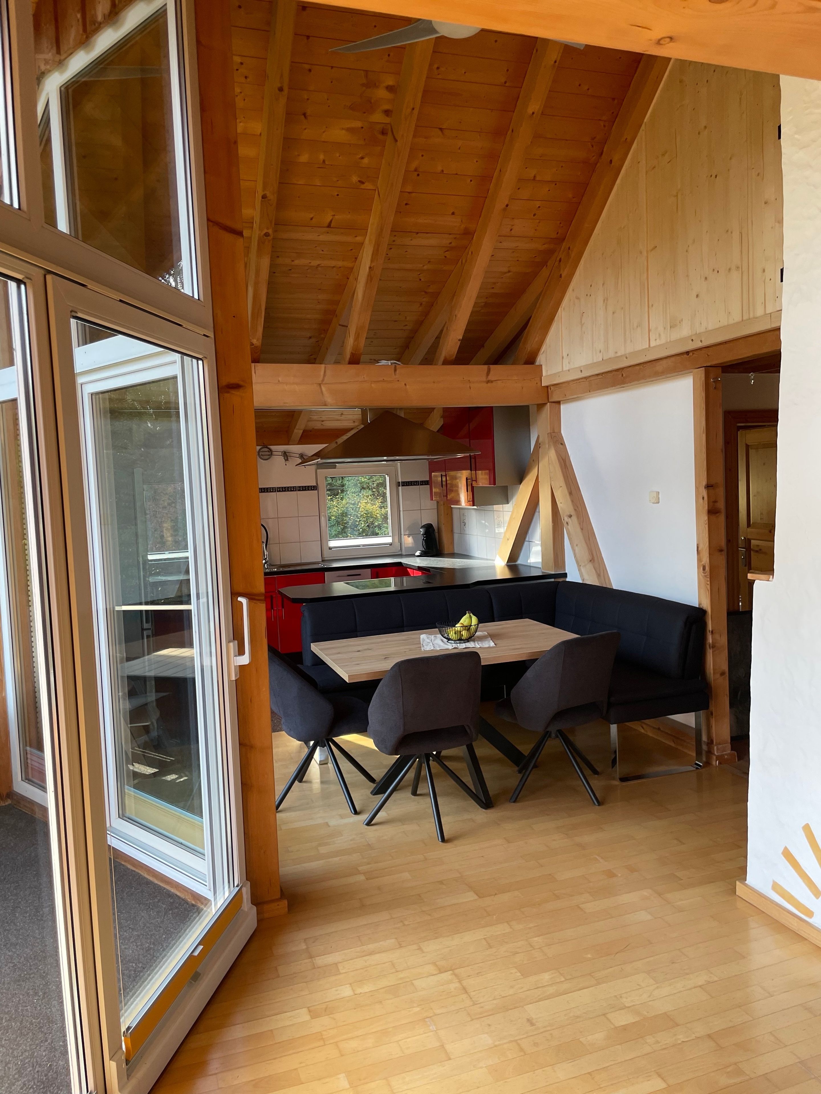 Eine moderne Küche mit Kochinsel, Holzbalken und einem Essbereich mit Tisch und Stühlen.